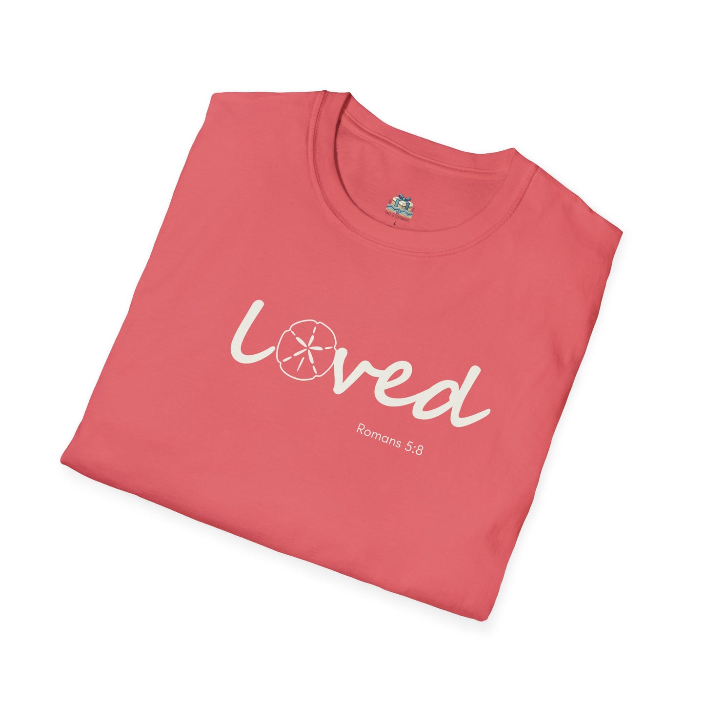 Folded pink t-shirt with 'Loved Romans 5:8' text on a white background