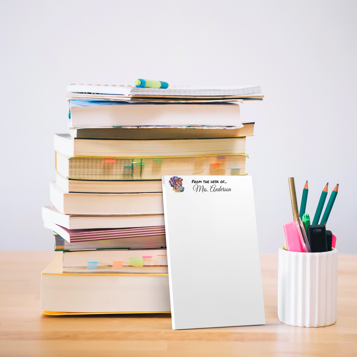 Notepad with teacher’s name next to a stack of books
