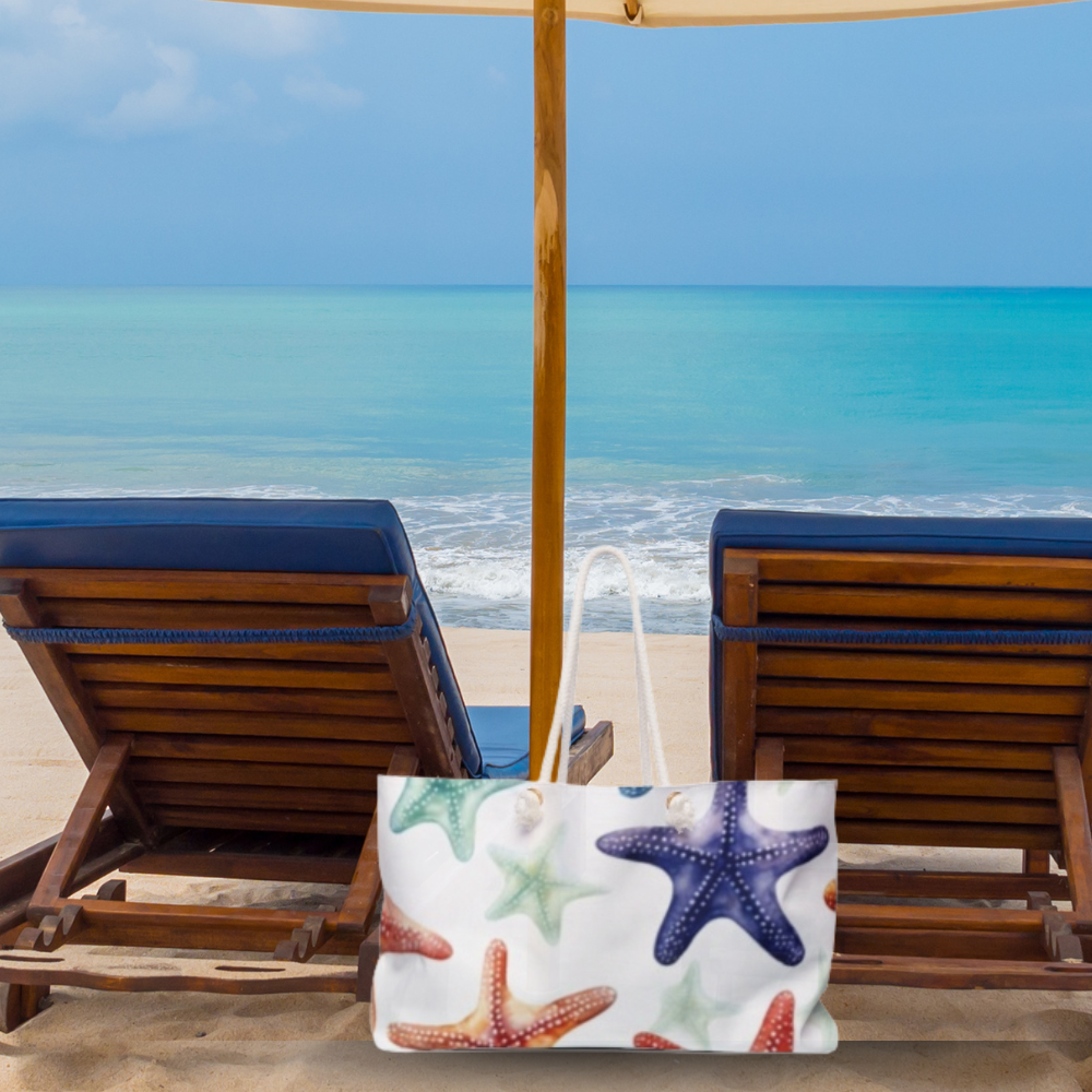 A colorful starfish-themed beach bag placed on a wooden chair with a beach and ocean in the background.