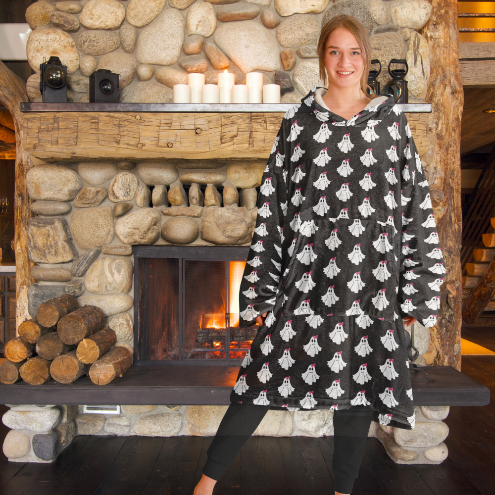 Person wearing a black hoodie with ghost patterns in front of a stone fireplace.