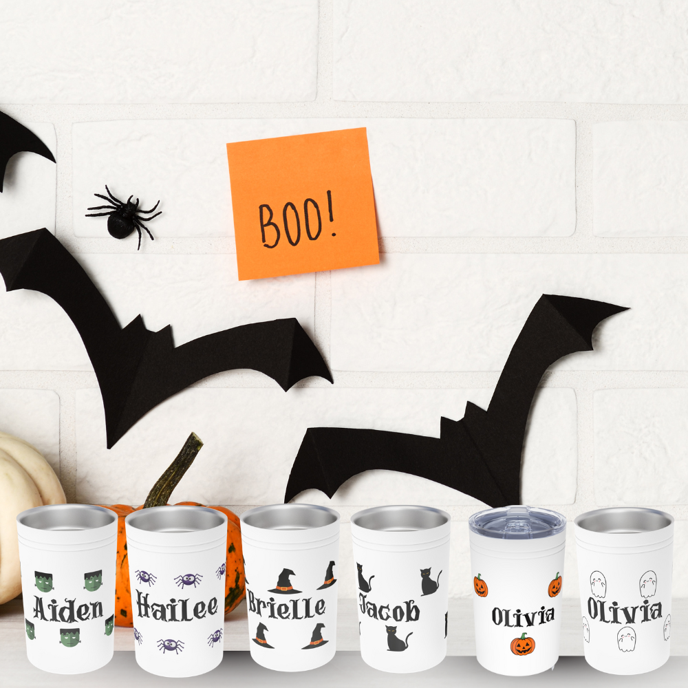 Set of personalized Halloween tumblers with names on a decorative background with bats and pumpkins.