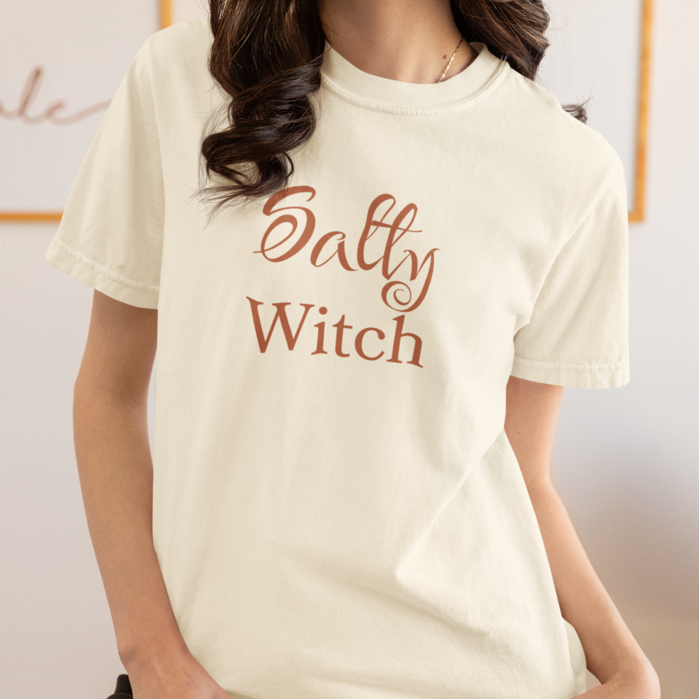 Person wearing a white t-shirt with 'Salty Witch' text in brown.