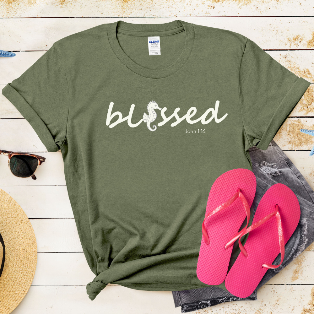 Green t-shirt with 'blessed' text, pink flip-flops, and sunglasses on a wooden surface