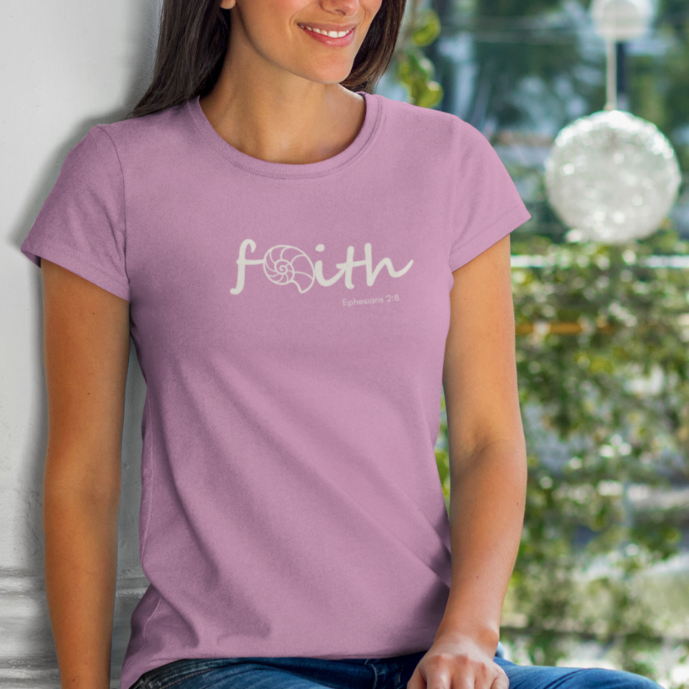 Woman wearing a purple t-shirt with 'faith' printed on it, sitting outdoors.