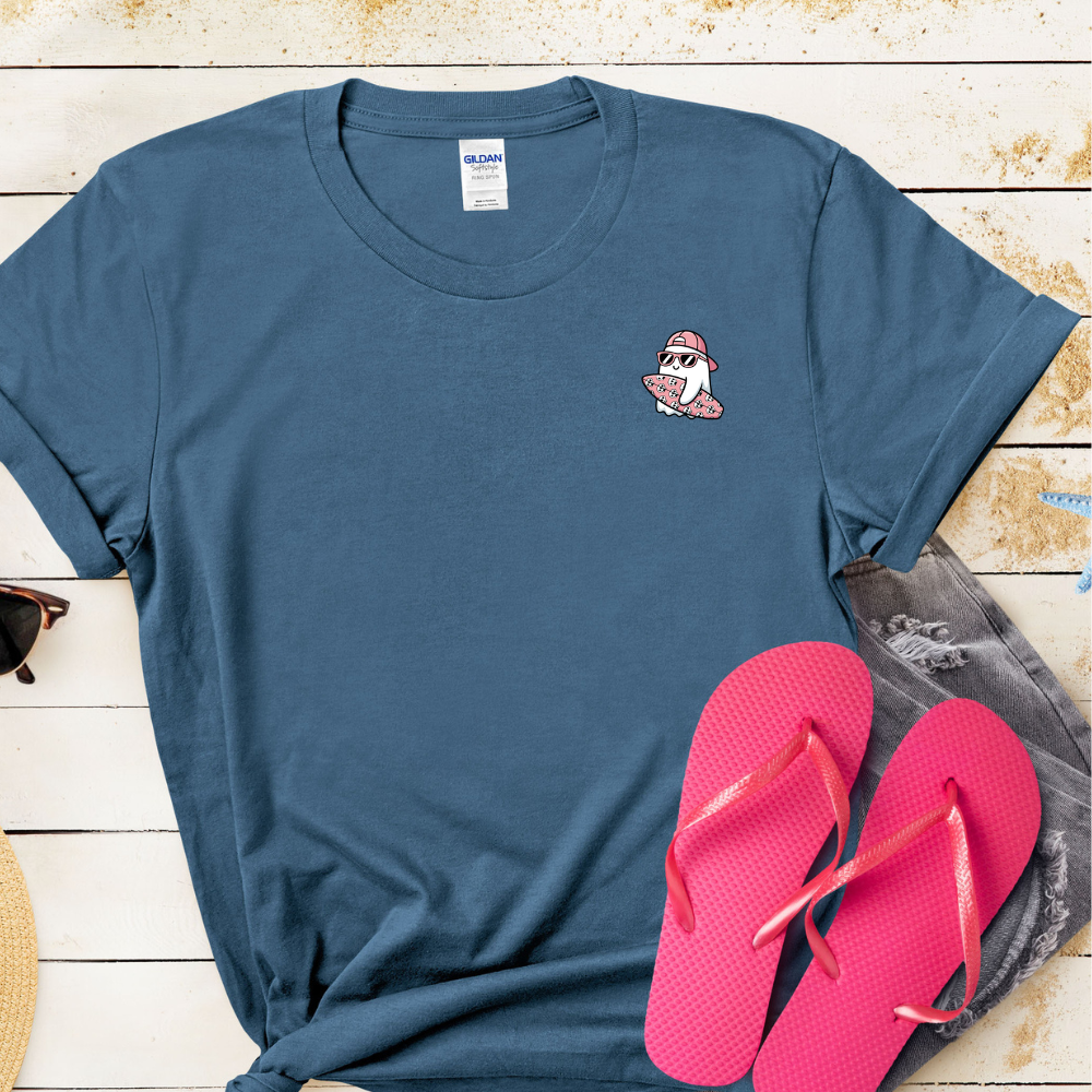 Blue t-shirt with a small graphic on a wooden surface with pink flip-flops.