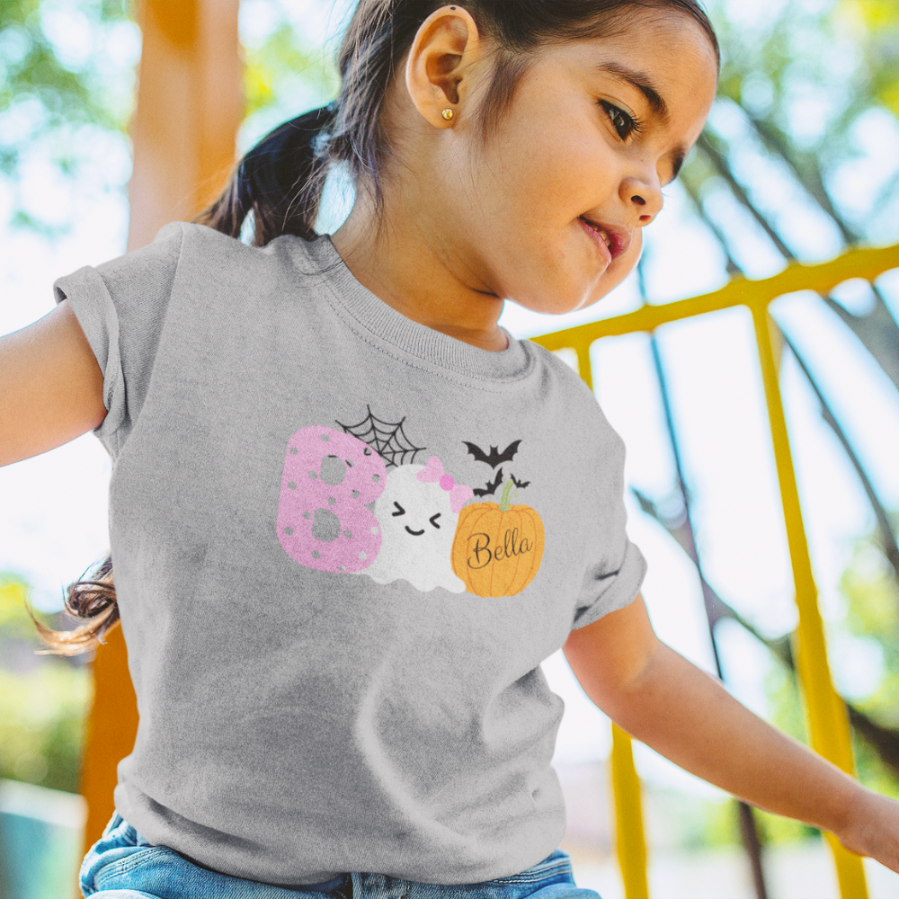 Child wearing a gray t-shirt with Halloween-themed design outdoors