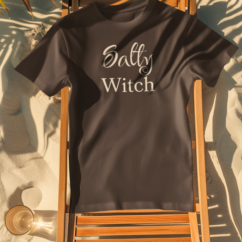 Black t-shirt with 'Salty Witch' text on a wooden chair on sand