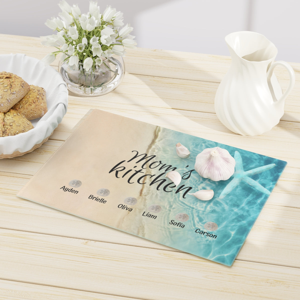 Custom Mom’s kitchen cutting board with sand and ocean design, featuring children's names on sand dollars.