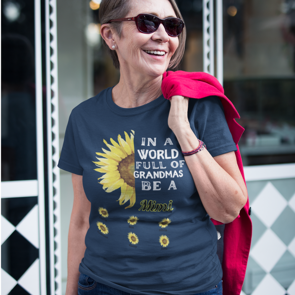 Elderly woman smiling in a navy blue t-shirt that reads "In a world full of grandmas be a Mimi" with sunflowers