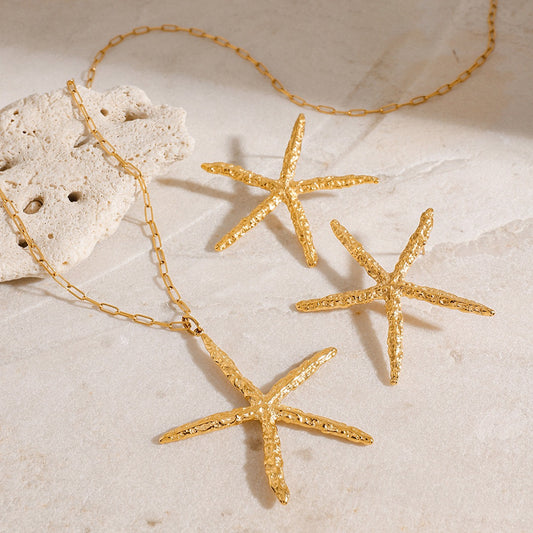 Gold starfish necklace on a sandy surface