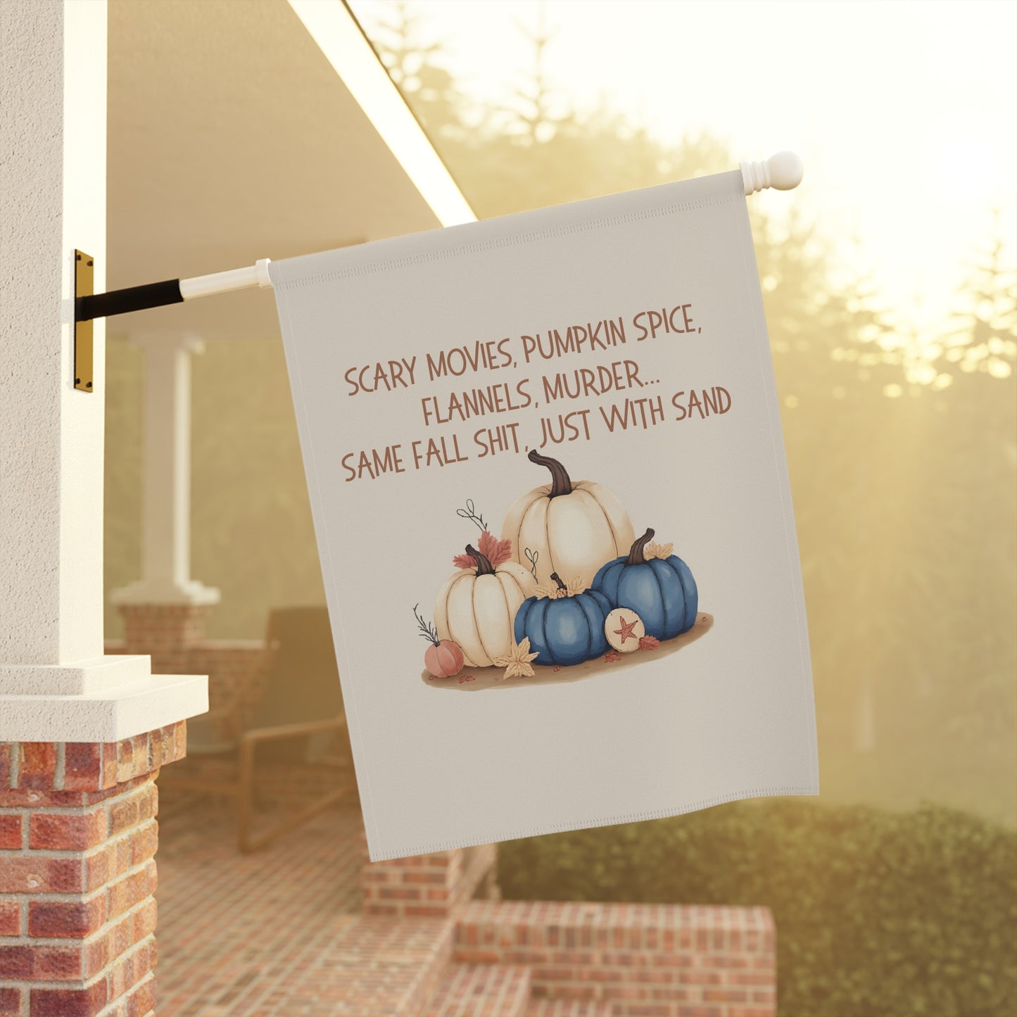 Decorative garden flag with pumpkins and text on a pole against a blurred outdoor background
