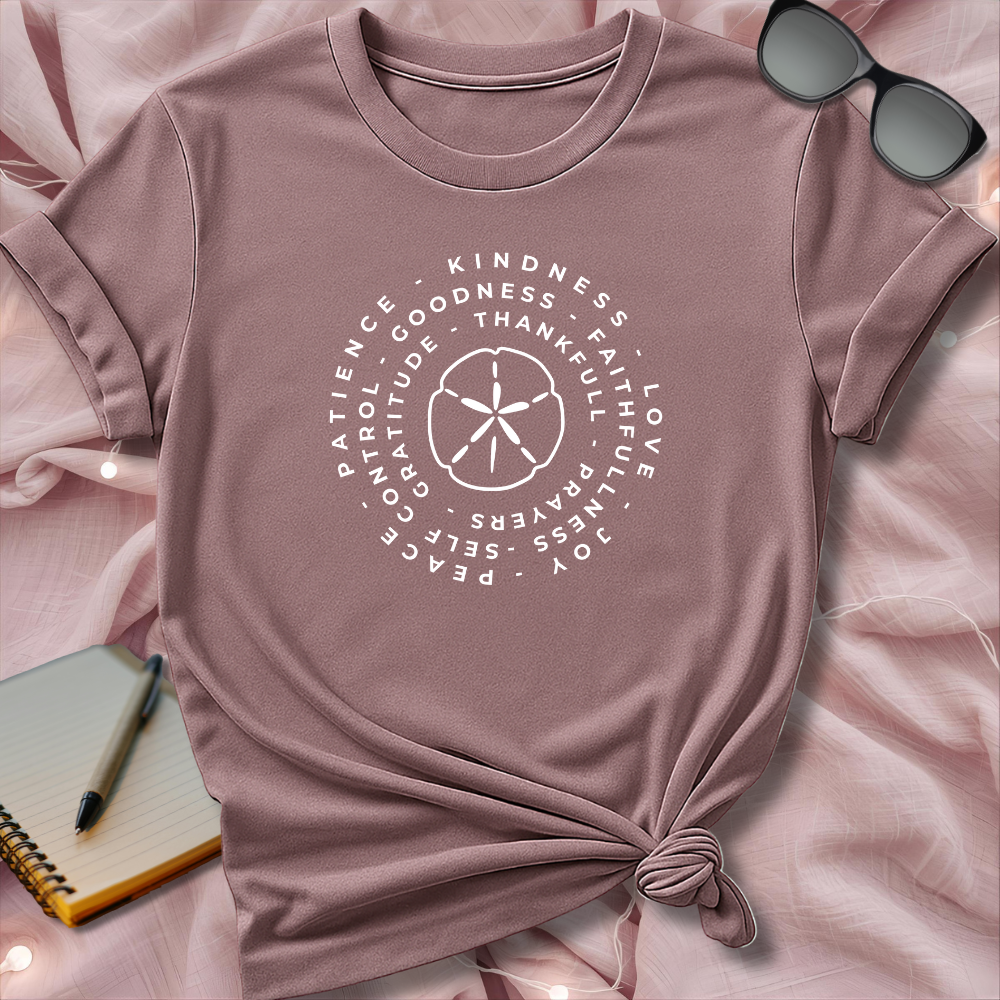 Pink t-shirt with motivational text design on a pink surface with sunglasses and notebook.