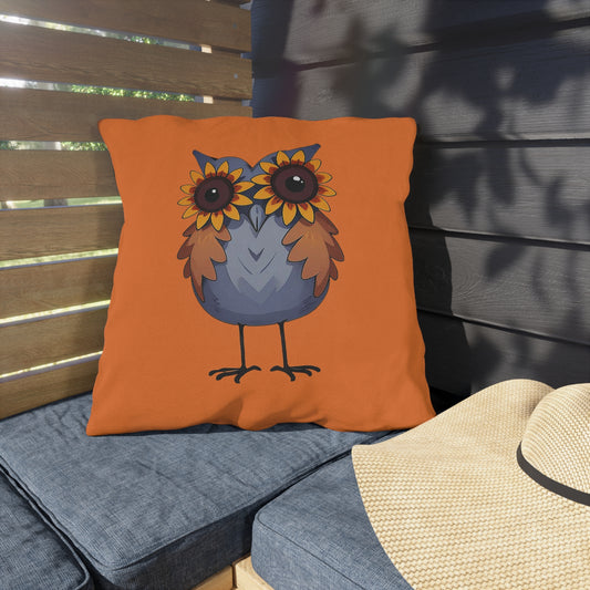Orange pillow with an owl design on a wooden bench