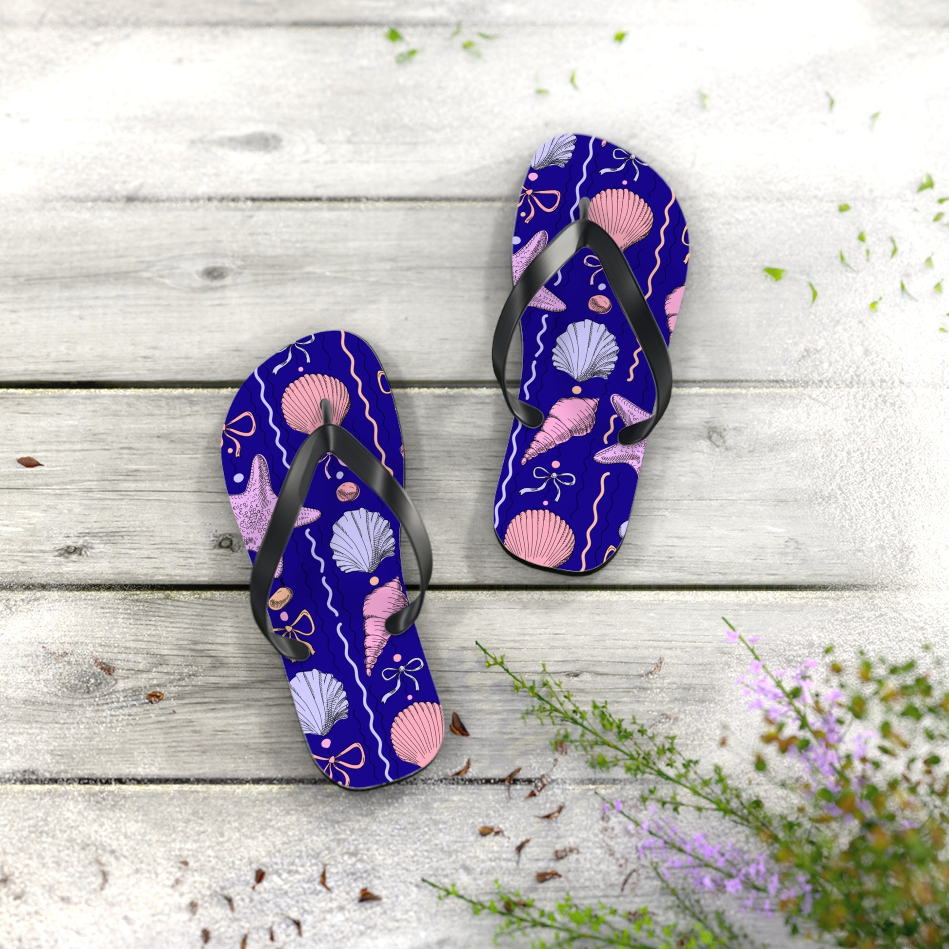 Pair of purple flip-flops with shell pattern on a wooden surface