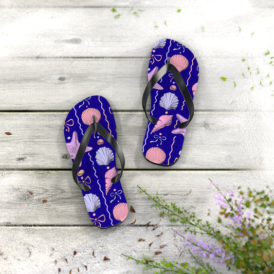 Pair of purple flip-flops with shell pattern on a wooden surface