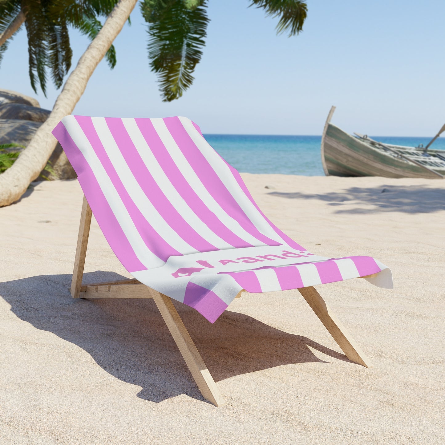 Beach chair with pink and white striped towel on a sandy beach with palm trees and ocean in the background.