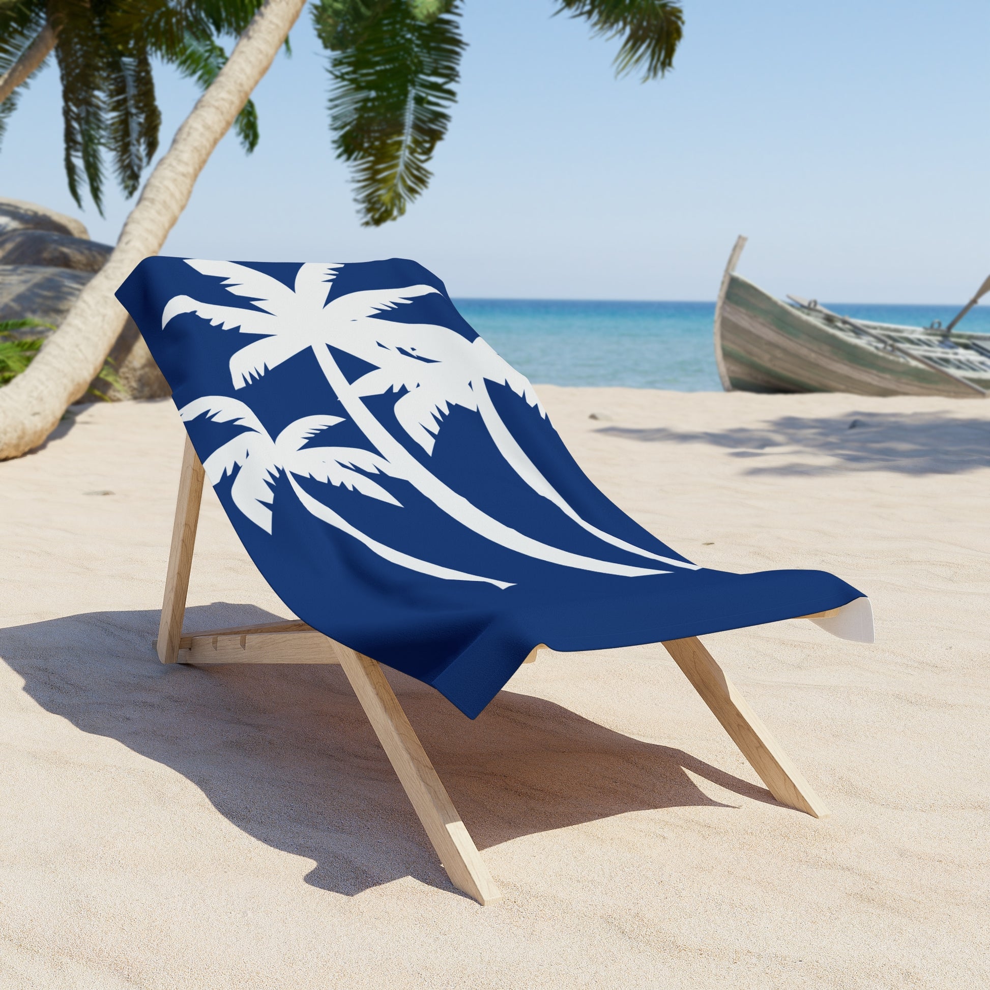 Blue beach towel with white palm tree design on a wooden chair at a tropical beach.