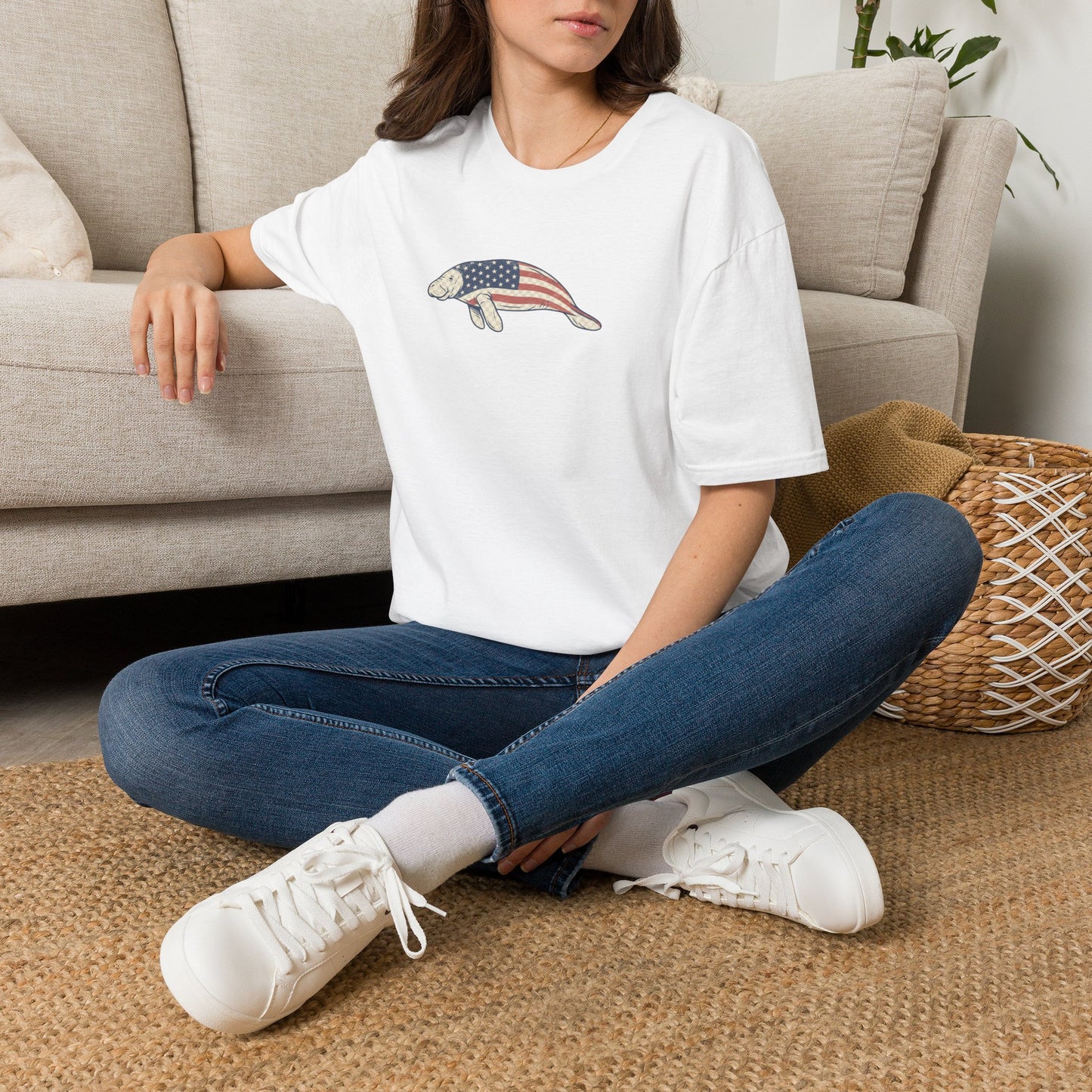Person wearing a white t-shirt with a graphic design sitting on the floor.