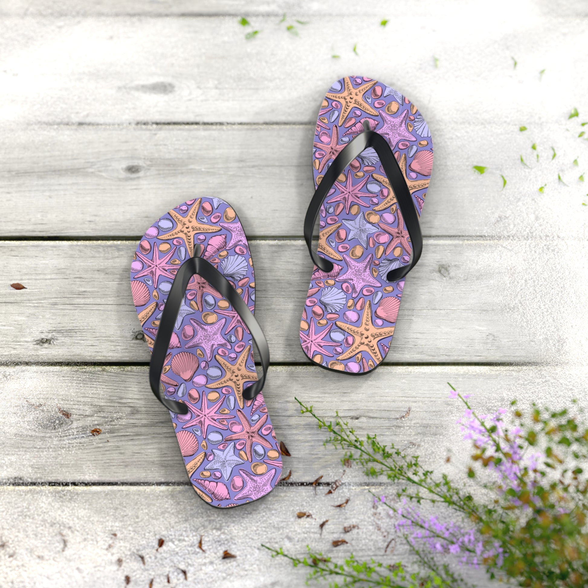 Pair of purple flip-flops with starfish design on a wooden surface.