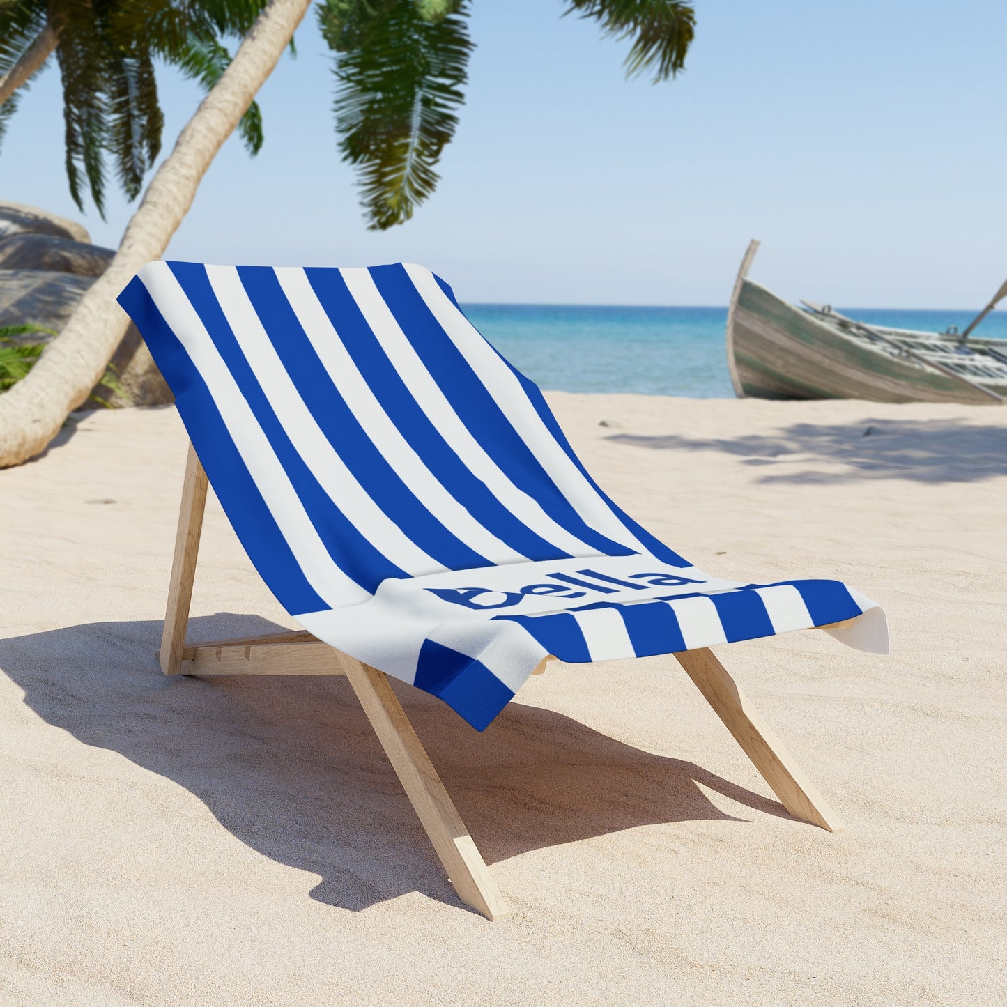 Blue and white striped towel on a wooden beach chair with palm trees and ocean in the background