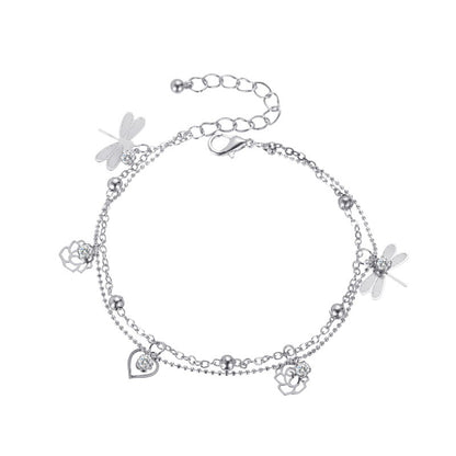 Elegant beach anklet with flower and dragonfly accents in soft lighting