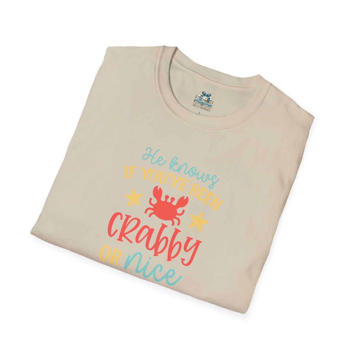 Folded beige t-shirt with colorful text and a crab graphic on a white background
