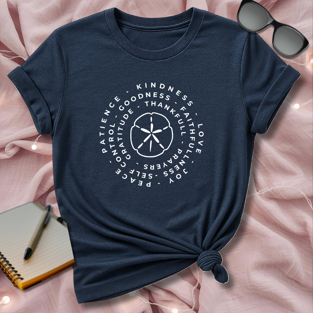 Navy blue t-shirt with motivational text design on a pink surface with sunglasses and notebook.
