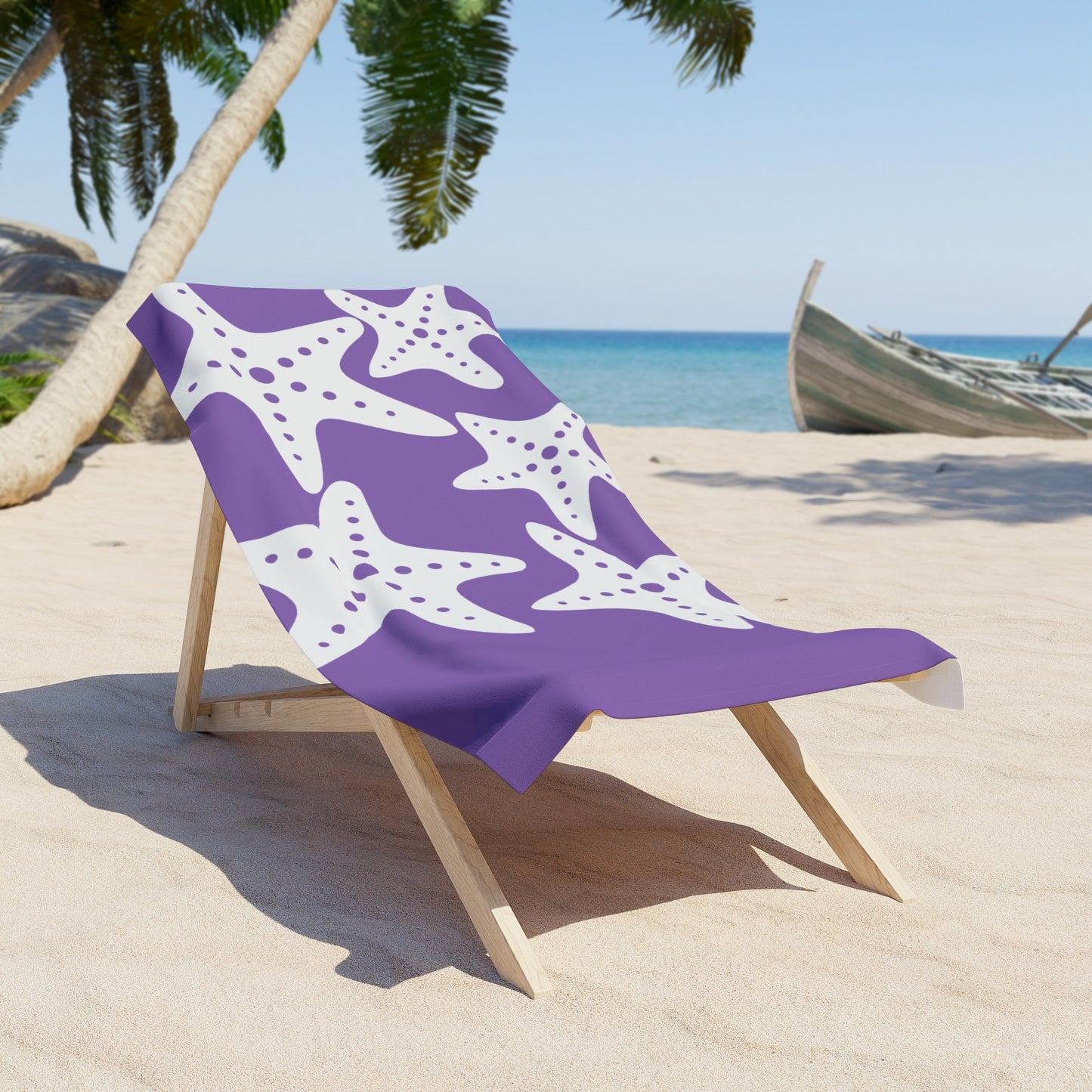 Purple beach towel with white starfish pattern on a wooden chair at a tropical beach.
