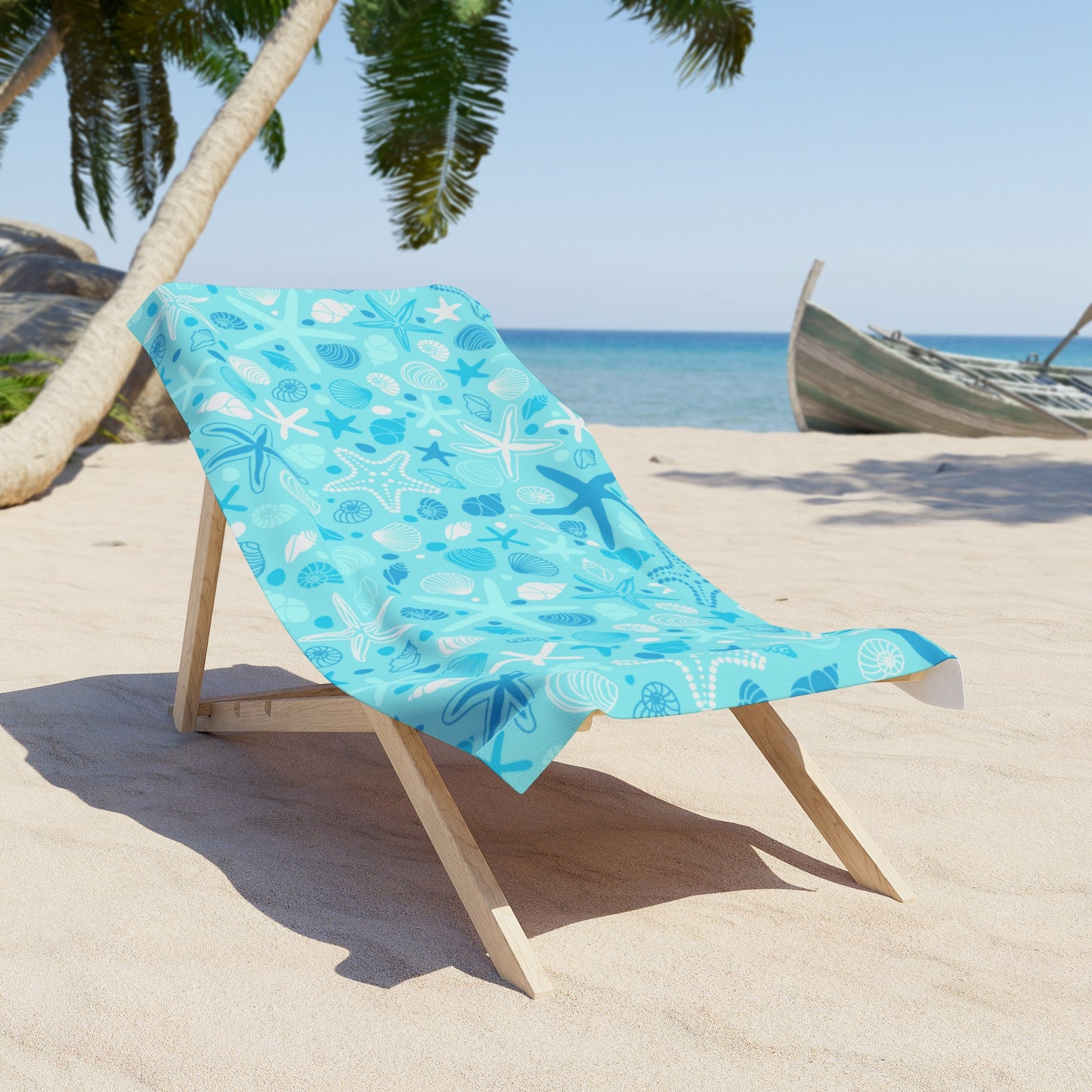 Beach chair with a blue towel featuring starfish and shells on a sandy beach.