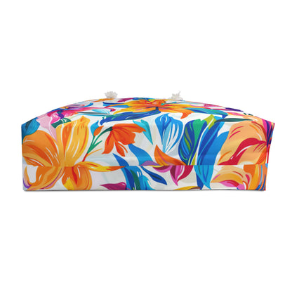 bottom side of oversized floral beach bag with colorful tropical flowers, white rope handles, displayed on a sandy beach background.