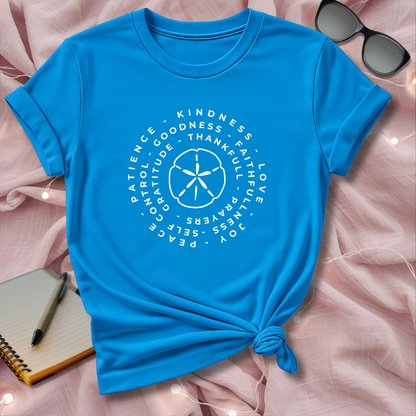 Blue t-shirt with white text and design on a pink surface with sunglasses and notebook.
