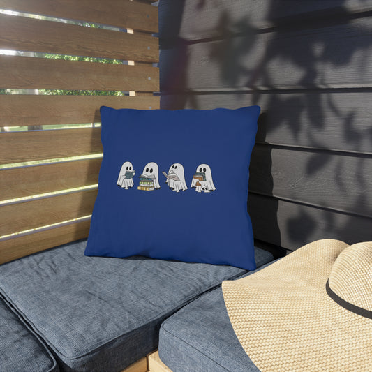 Blue pillow with cartoon ghosts on a gray cushioned bench outdoors.