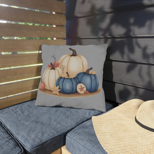 Decorative pillow with pumpkins on a cushioned bench outdoors.