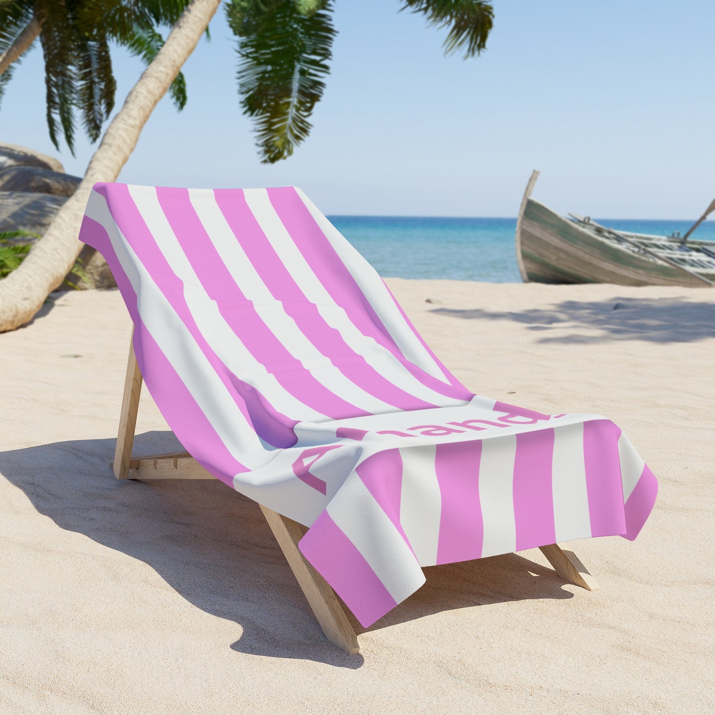 Beach chair with pink and white striped towel on a sandy beach with palm trees and ocean in the background.