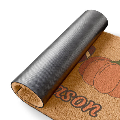 Doormat with 'Wilson' printed on it, featuring pumpkins, rolled up on a white background.