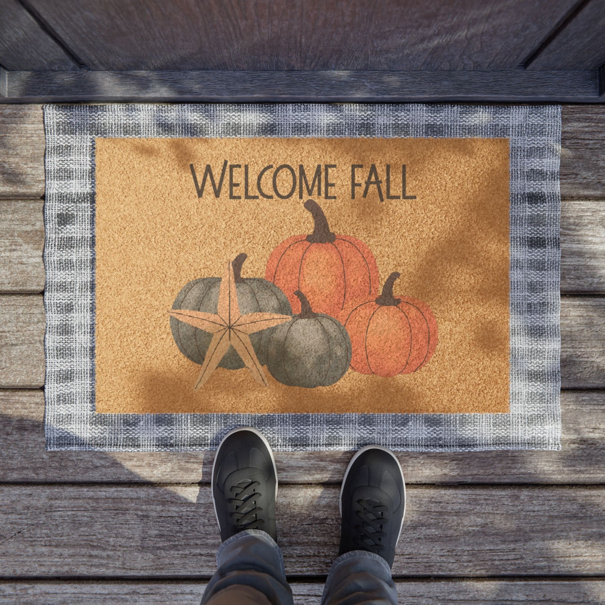 Doormat with 'Welcome Fall' text and pumpkins on a wooden floor.