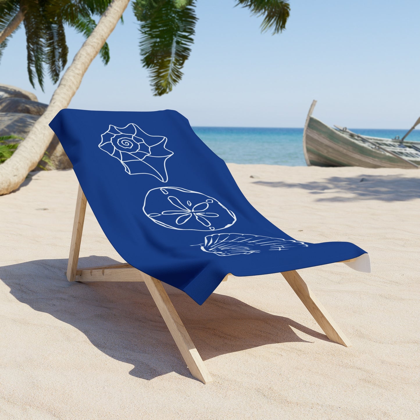 Blue beach towel with white shell designs on a wooden chair at a tropical beach.
