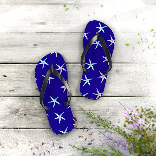 Blue flip-flops with starfish pattern on a wooden surface with flowers.