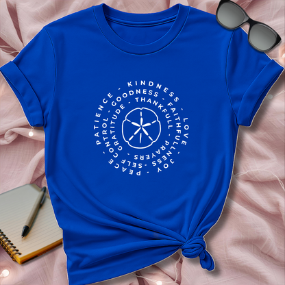 Blue t-shirt with white text and design on a pink surface with sunglasses and notebook.