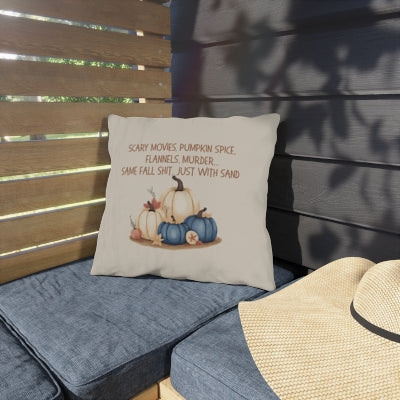 Decorative pillow with pumpkins and text on a blue cushion against a wooden wall.