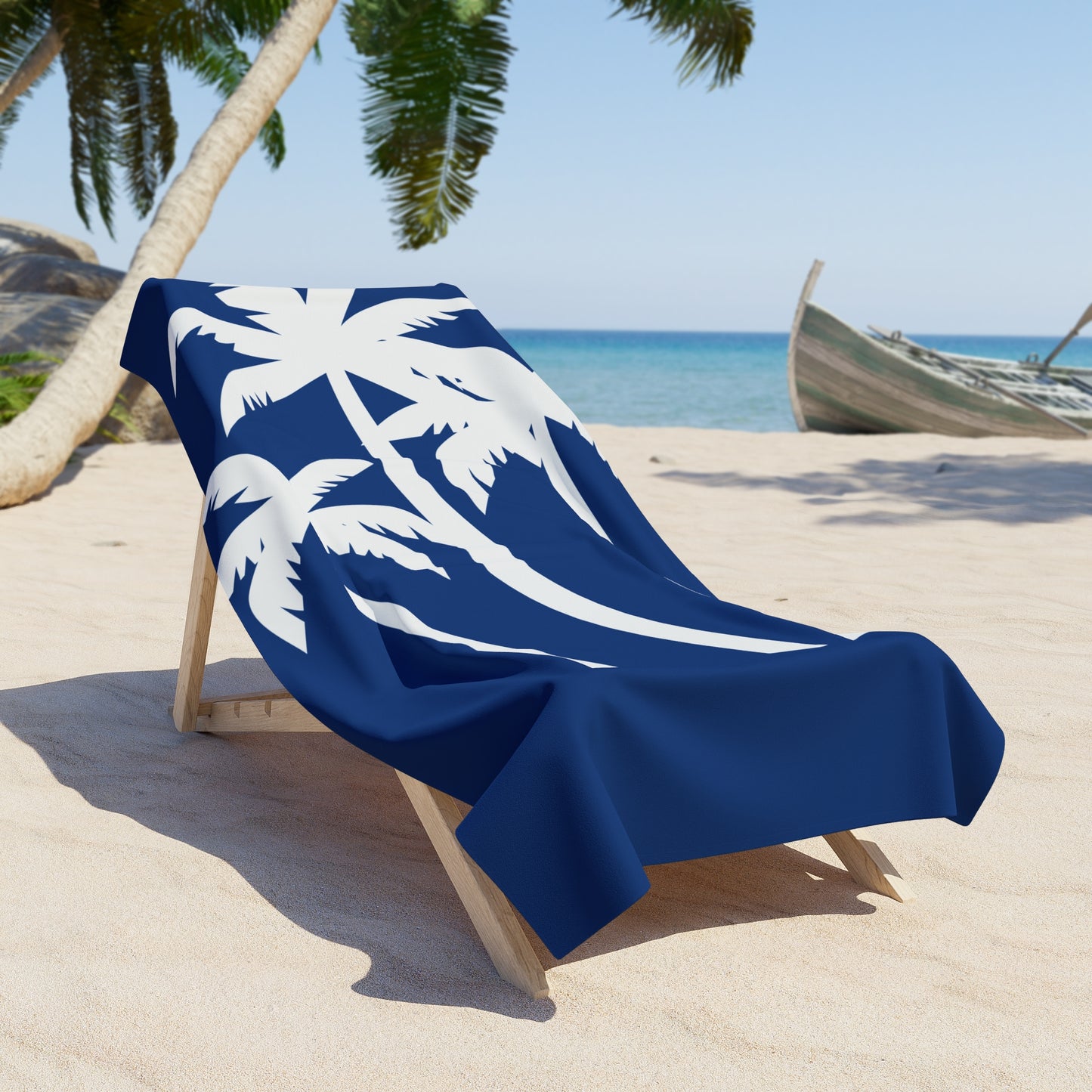 Blue beach towel with white palm tree design on a wooden chair at a tropical beach.