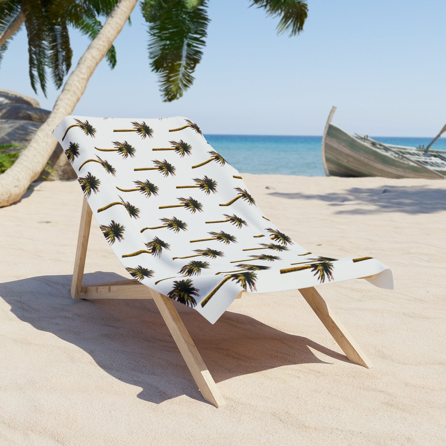 Beach towel with palm tree pattern on a wooden stand on a sandy beach.