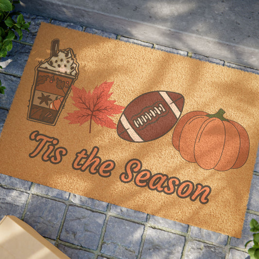Doormat with autumn-themed design featuring a coffee cup, leaf, football, and pumpkins with 'Tis the Season text.