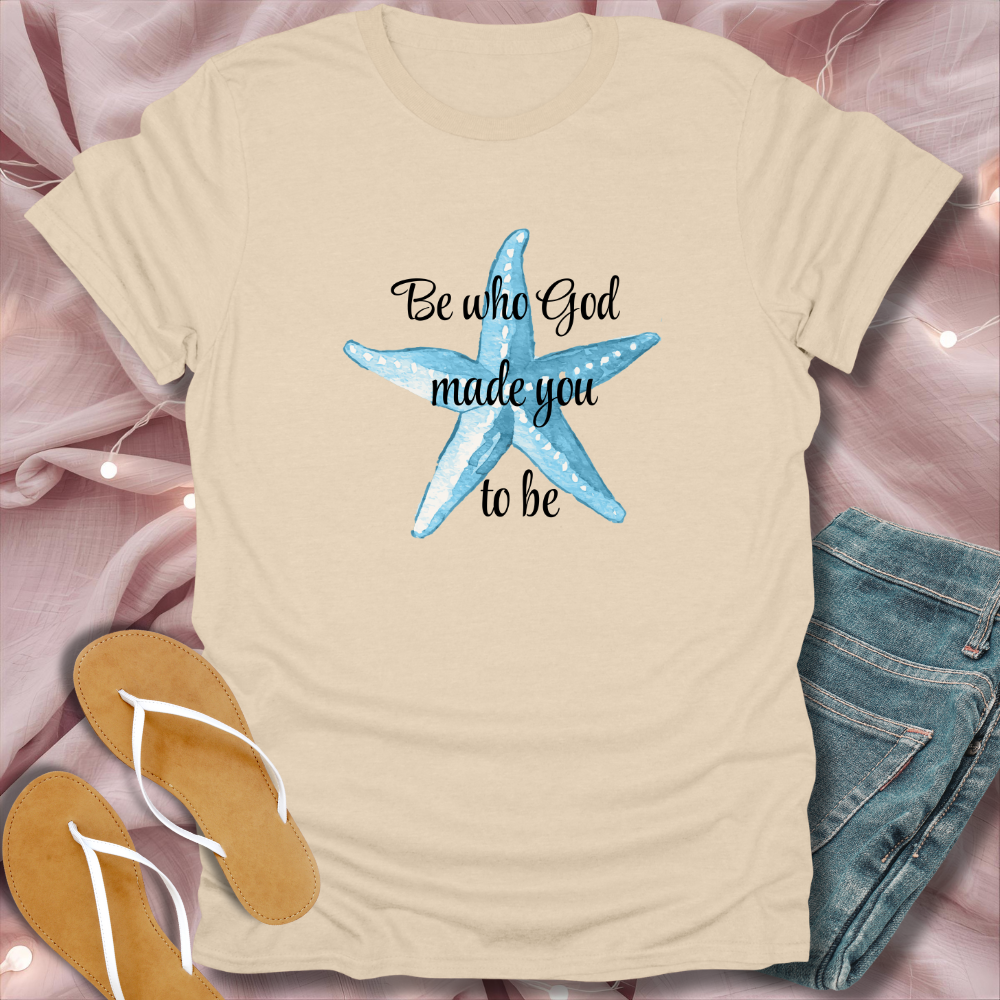 Beige t-shirt with blue starfish design and text on a pink fabric background