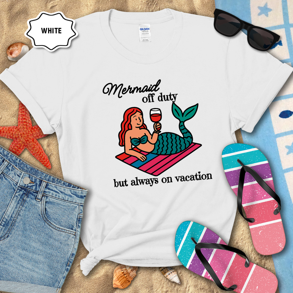White t-shirt with mermaid graphic and text on a beach-themed background