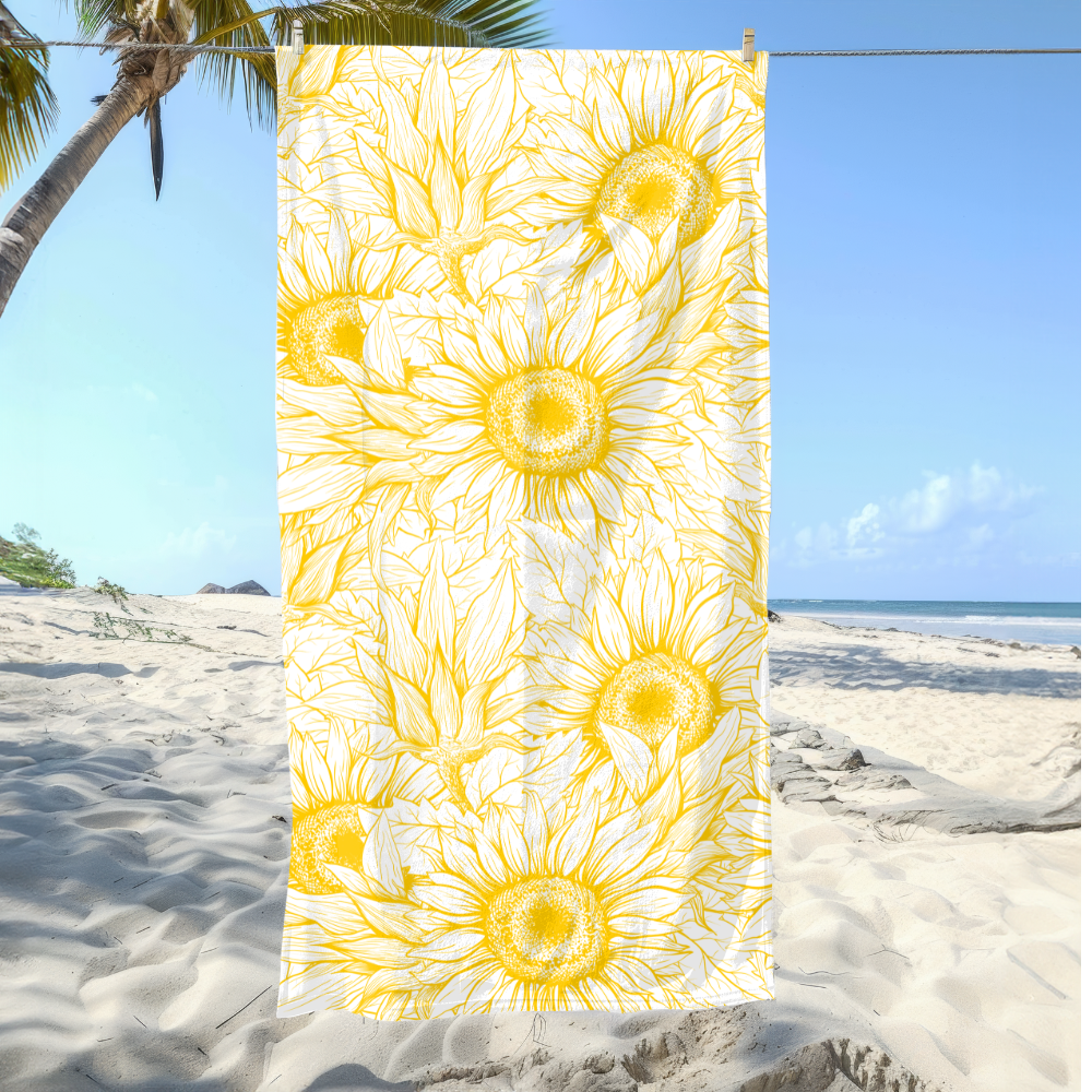 Yellow sunflower patterned towel on a sandy beach with palm trees and blue sky.