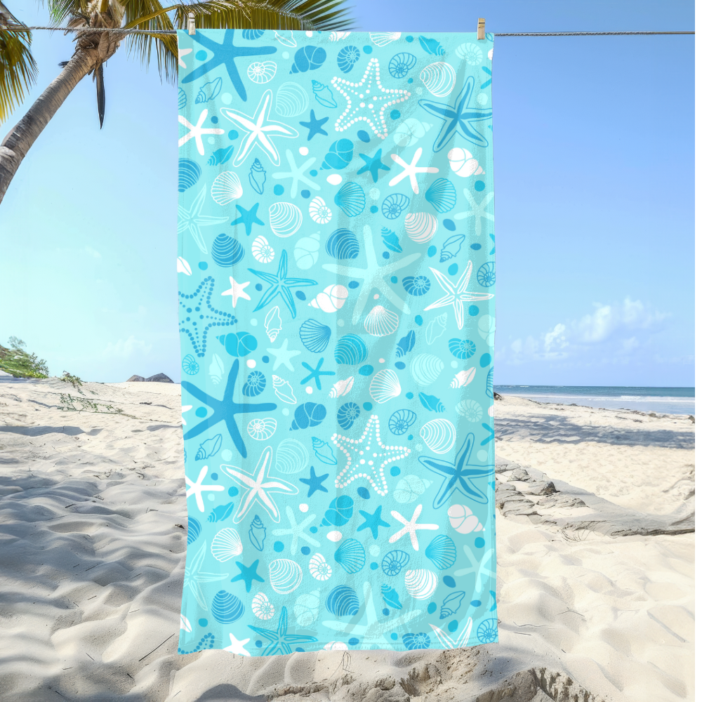 Beach towel with starfish and shell pattern on a sandy beach