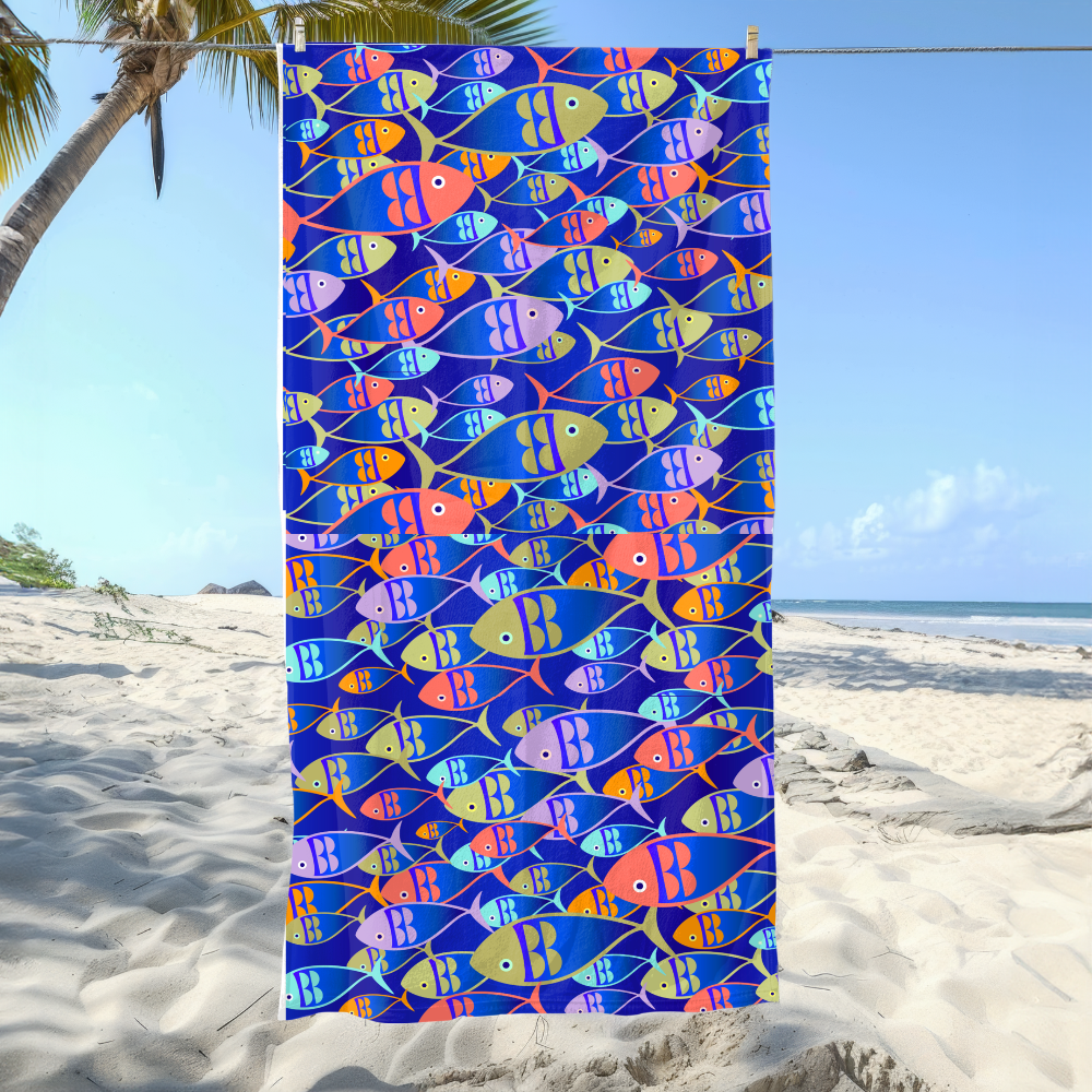 Colorful fish-patterned towel hanging on a beach with palm trees and ocean in the background.