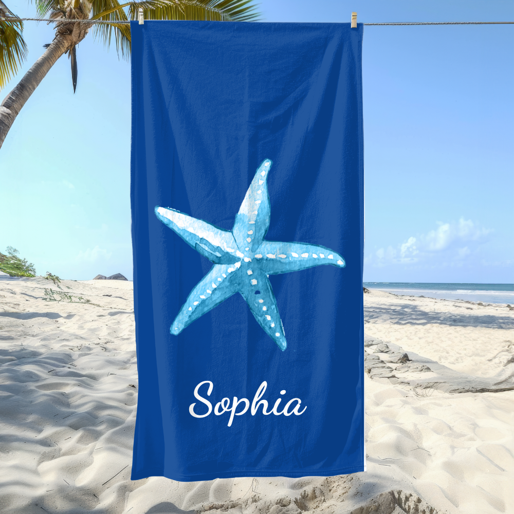 Blue towel with a starfish design and 'Sophia' text on a beach
