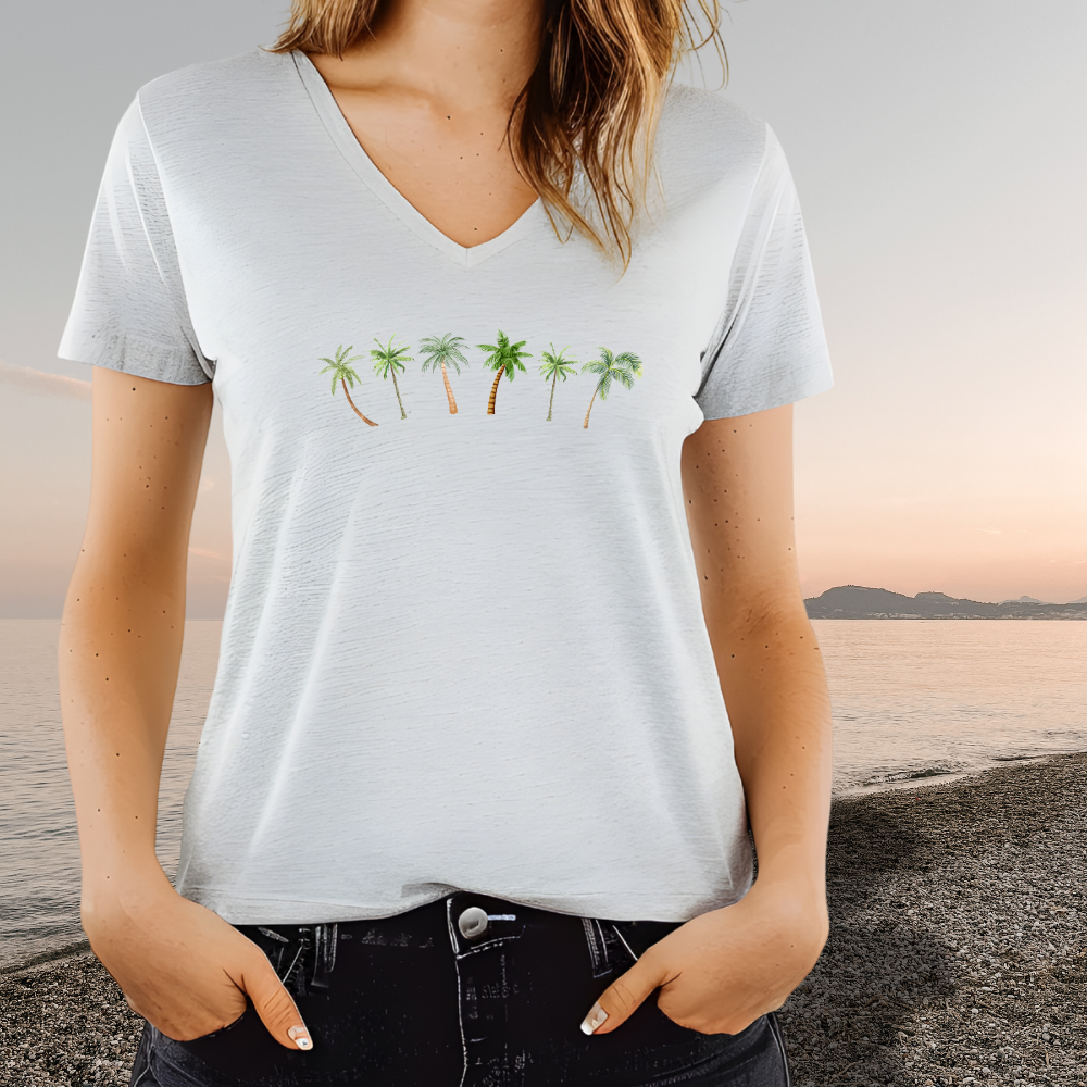 Person wearing a white t-shirt with palm tree design at a beach.